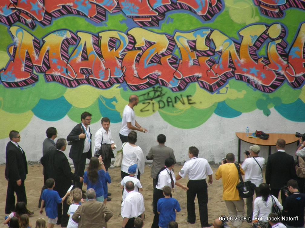 Zidan składa autograf na murze pod napisem uwierz w marzenia.