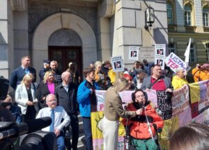 Grupa osób z transparentami protestuje przed Kancelarią Prezesa Rady Ministrów, domagając się uchwalenia ustawy o asystencji osobistej.